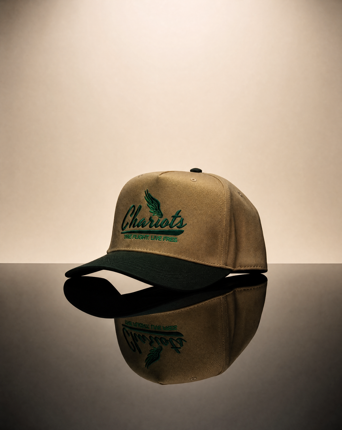 A beige baseball cap with a dark green visor and green embroidered text reading 'Chariots' on the front, displayed on a reflective dark surface against a warm beige background.