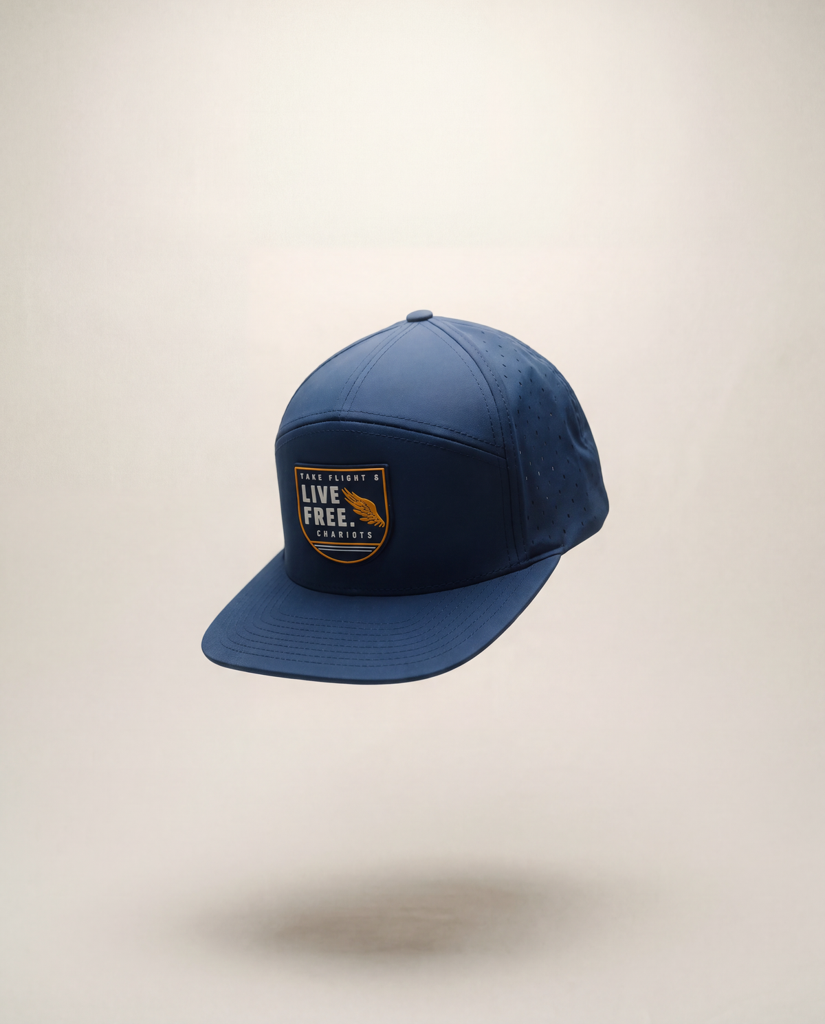 A navy blue baseball cap with a curved brim, featuring a front patch that reads 'TAKE FLIGHT LIVE FREE.